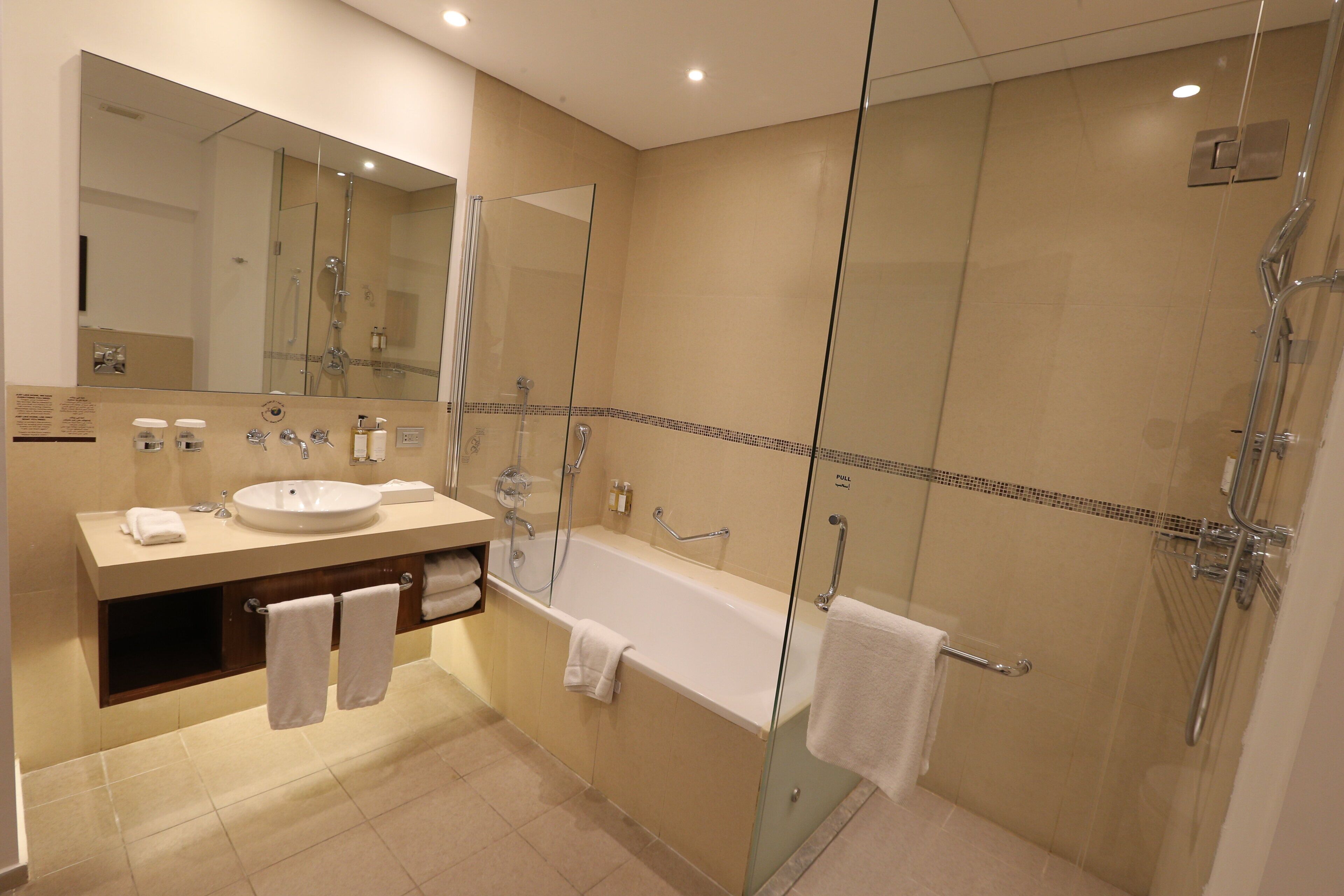 A modern bathroom with a glass-enclosed shower, a bathtub, and a vanity with a sink and mirror.