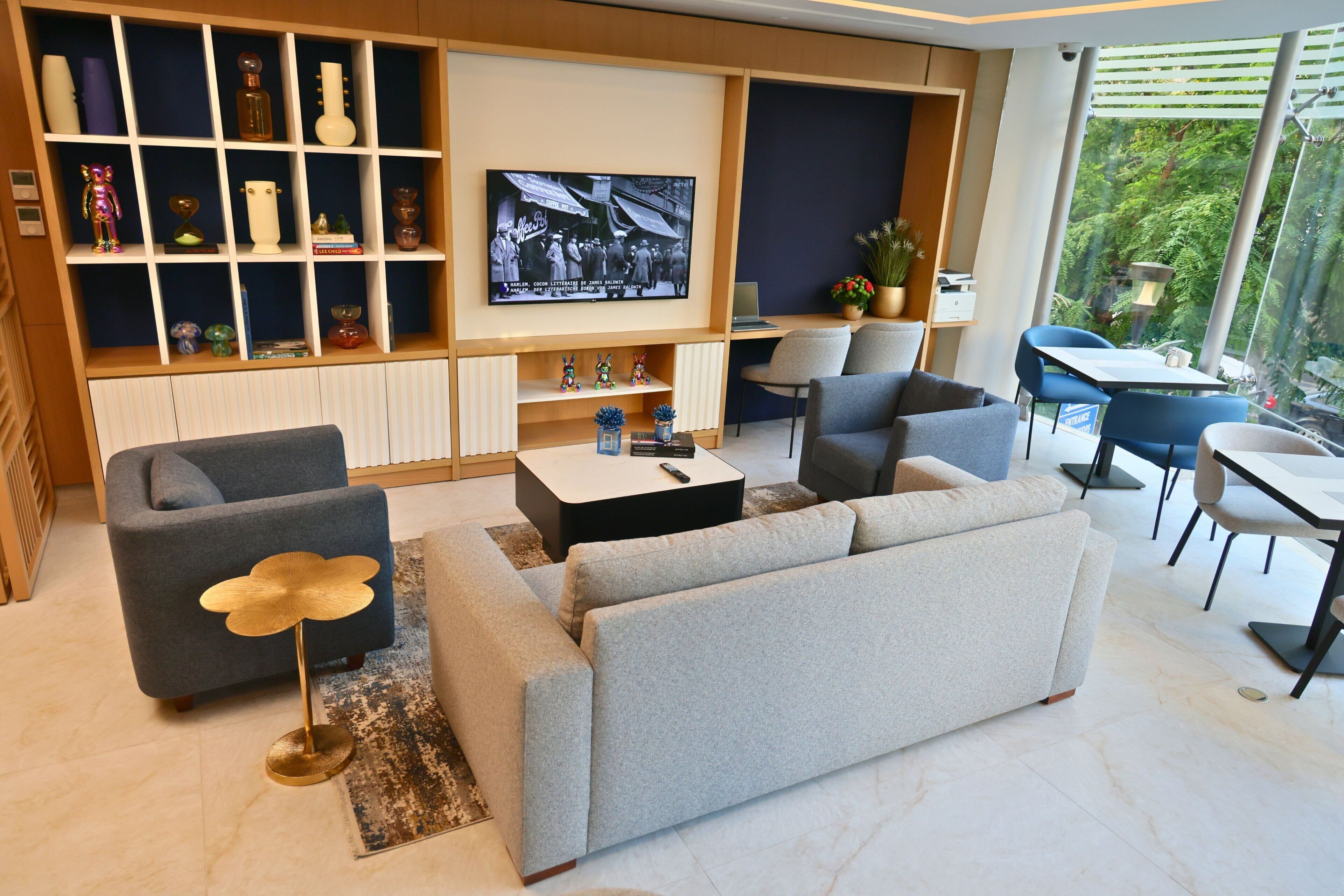 A modern living room with a sofa, armchairs, a coffee table, a TV, and a bookshelf.