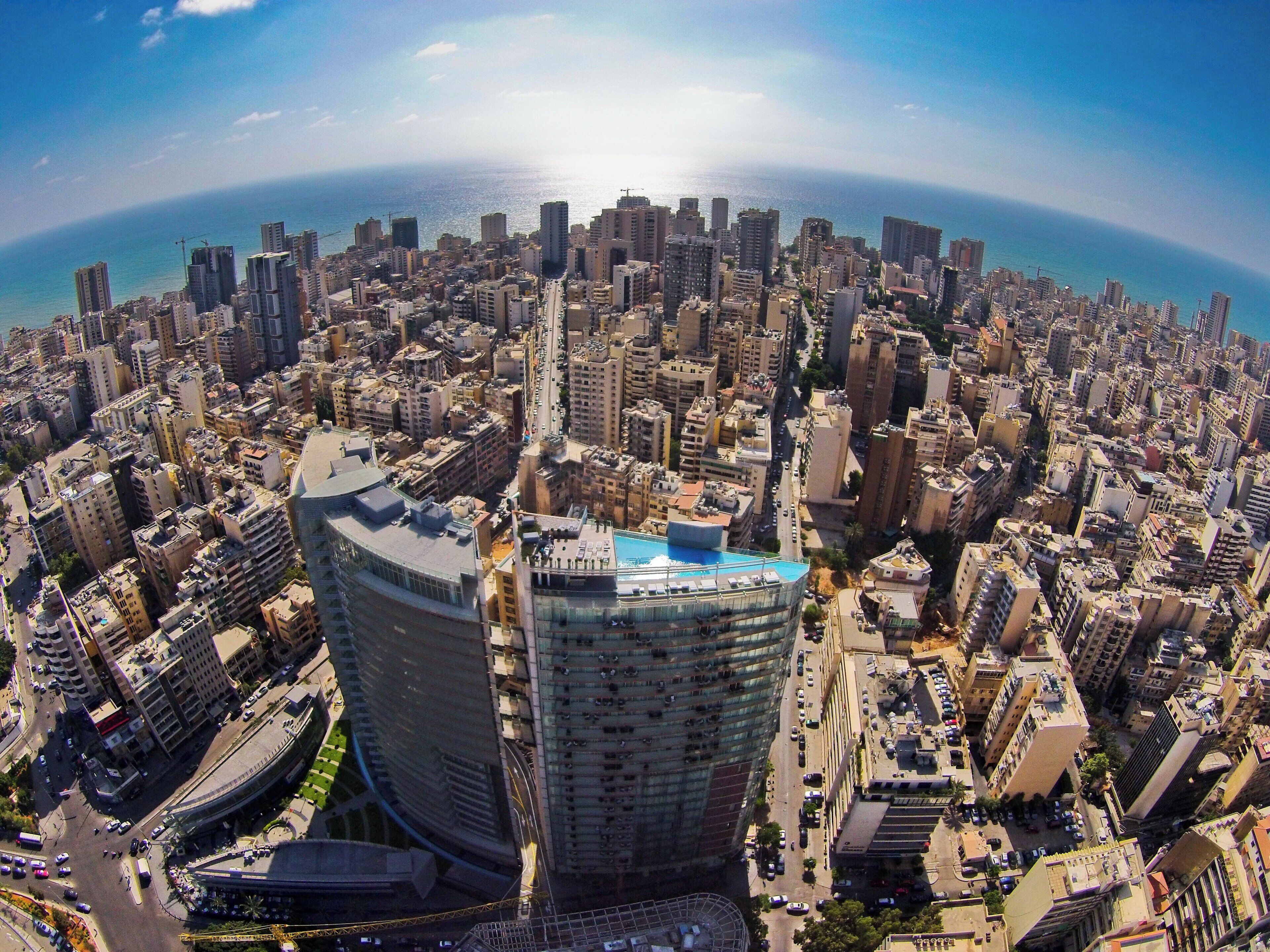 A cityscape with a prominent curved building featuring a rooftop pool, surrounded by dense urban architecture.