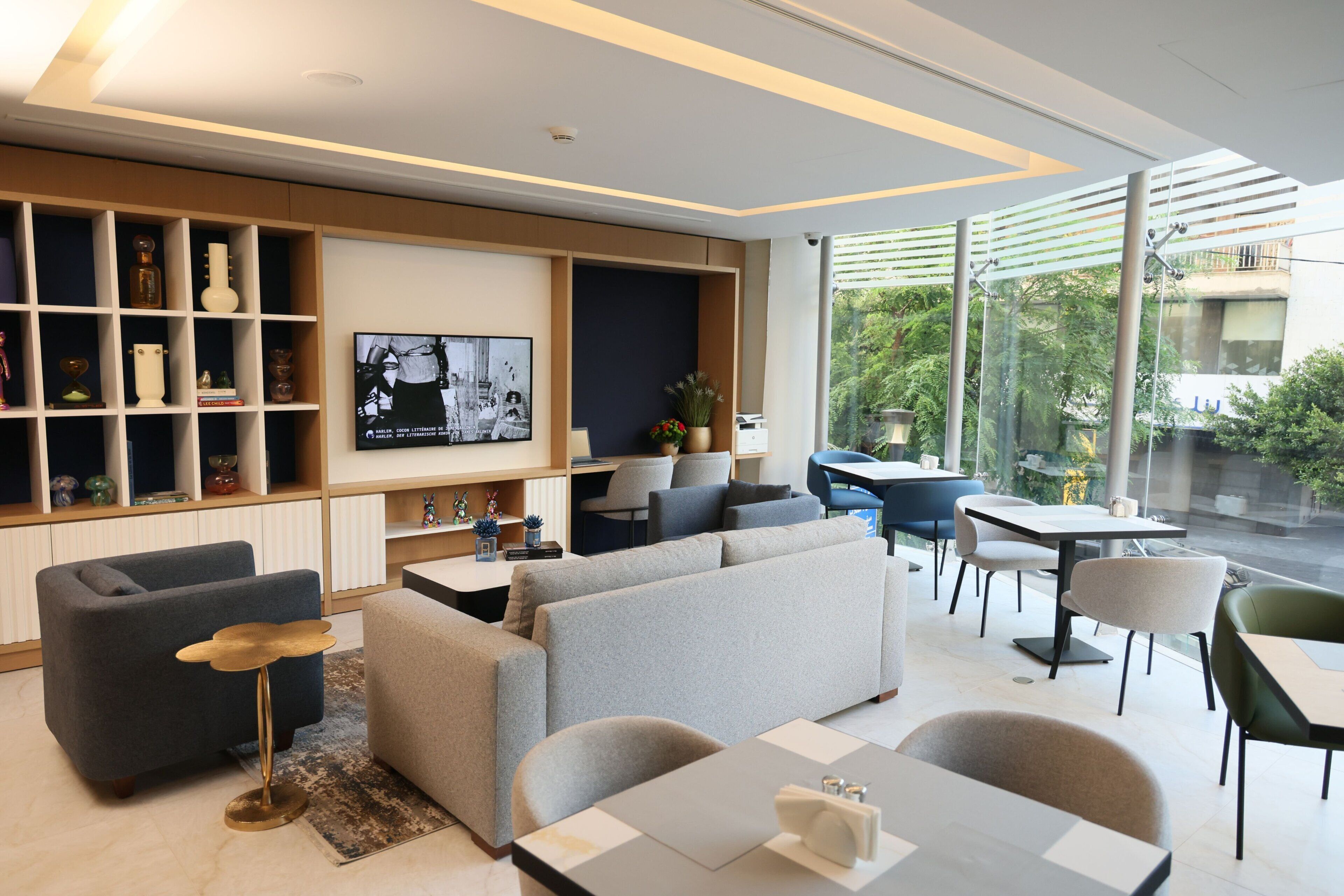 A modern living room with a sofa, armchairs, a coffee table, and a TV mounted on the wall.