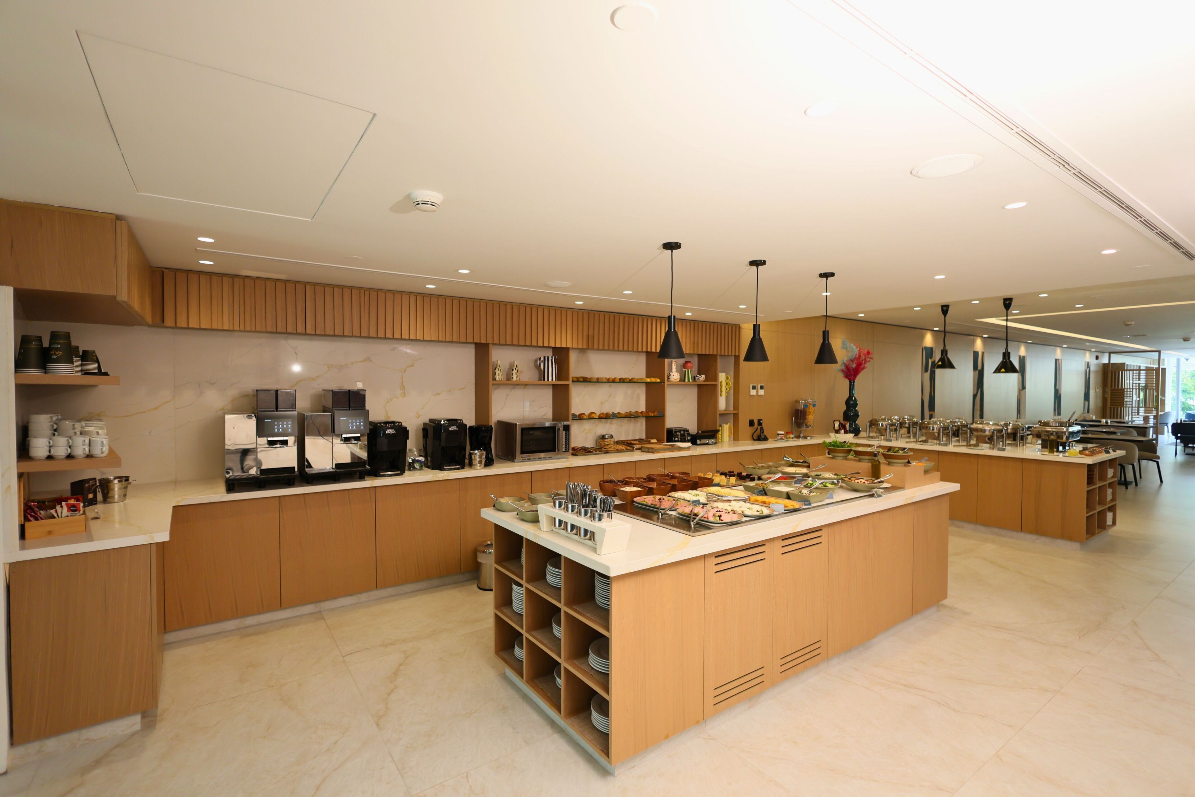 A modern kitchen with wooden cabinets, a central island with food items, and overhead pendant lighting.