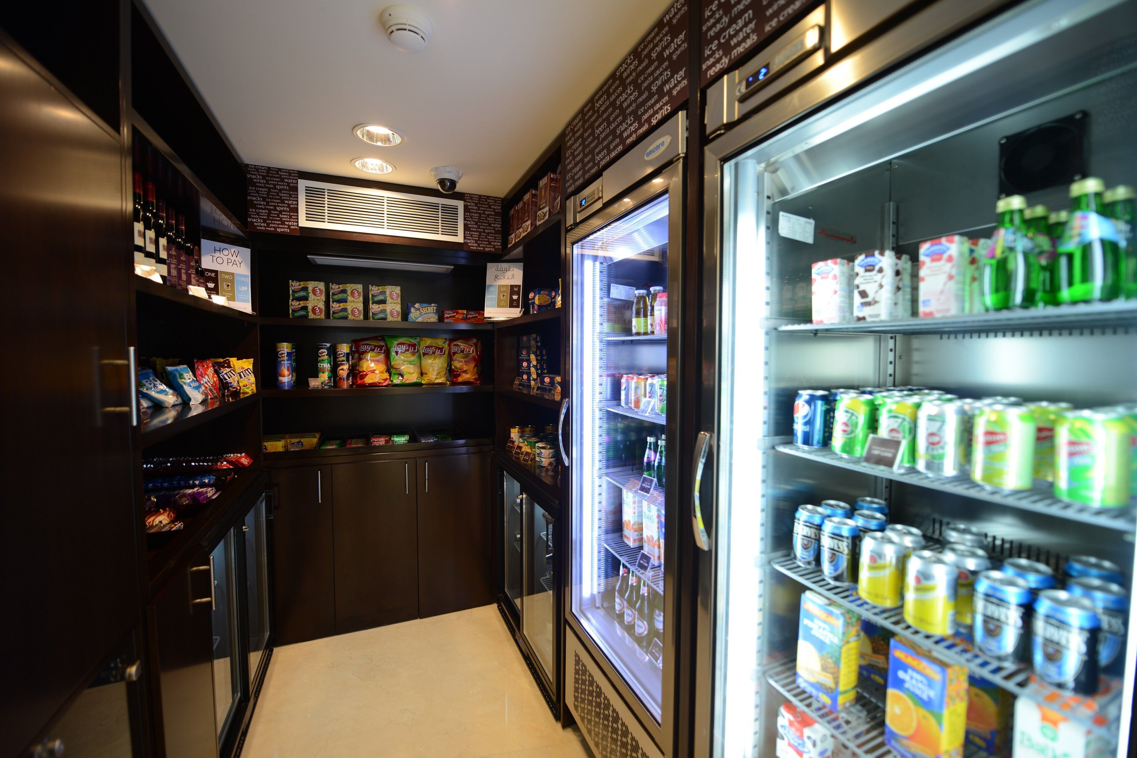 A narrow corridor with vending machines and refrigerated sections containing beverages and snacks.