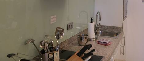 A modern kitchen with a stainless steel range hood, a built-in sink, and a granite countertop.
