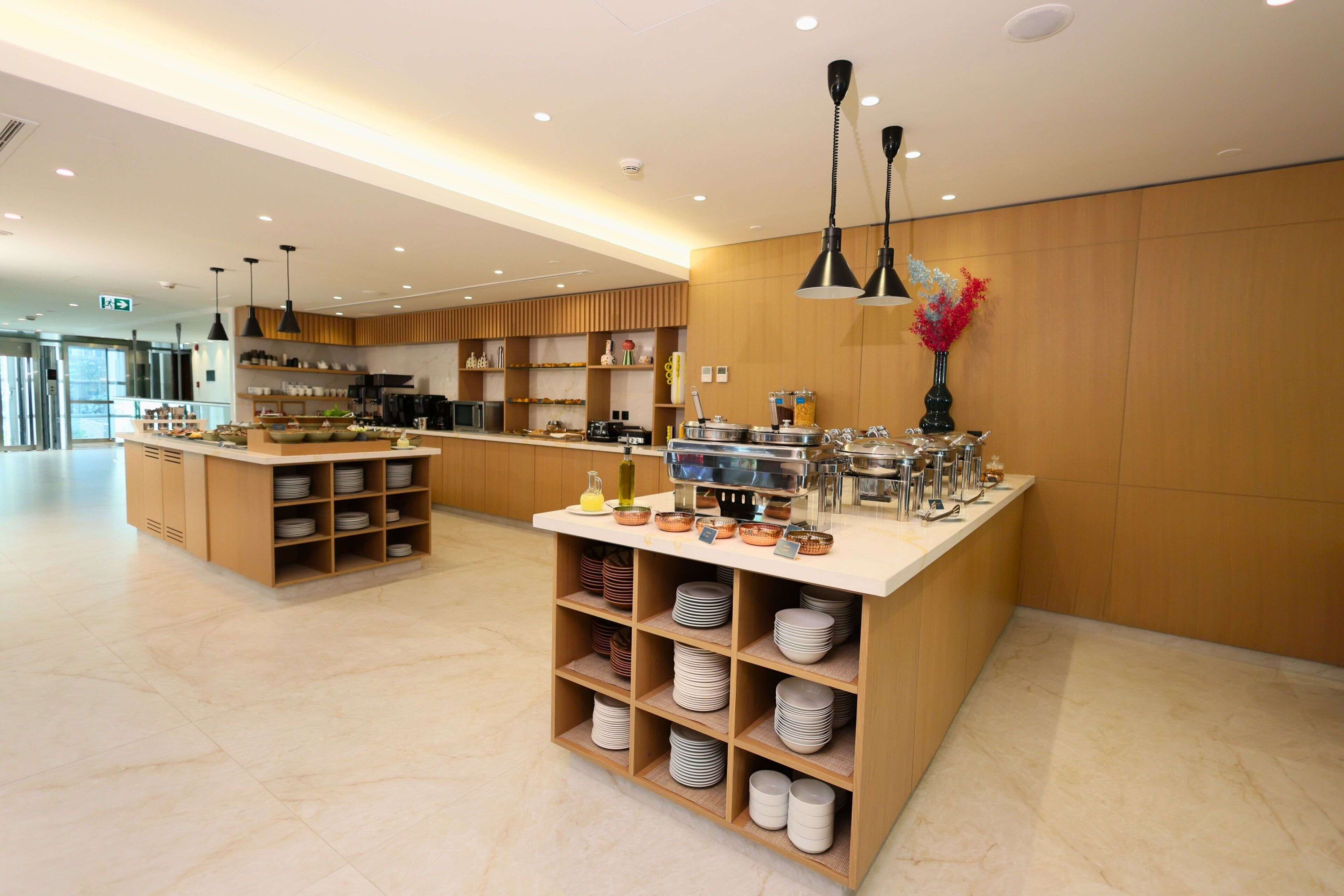 A modern kitchen area with a central island, wooden shelves, and a variety of kitchen appliances.