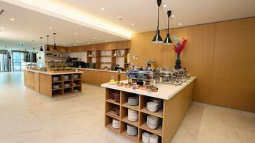 A modern kitchen area with a central island, wooden shelves, and a variety of kitchen appliances.