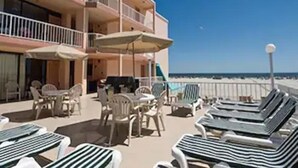 A beachfront hotel with multiple balconies, lounge chairs, and umbrellas. - Beau Rivage Beach Resort (Wildwood Crest)