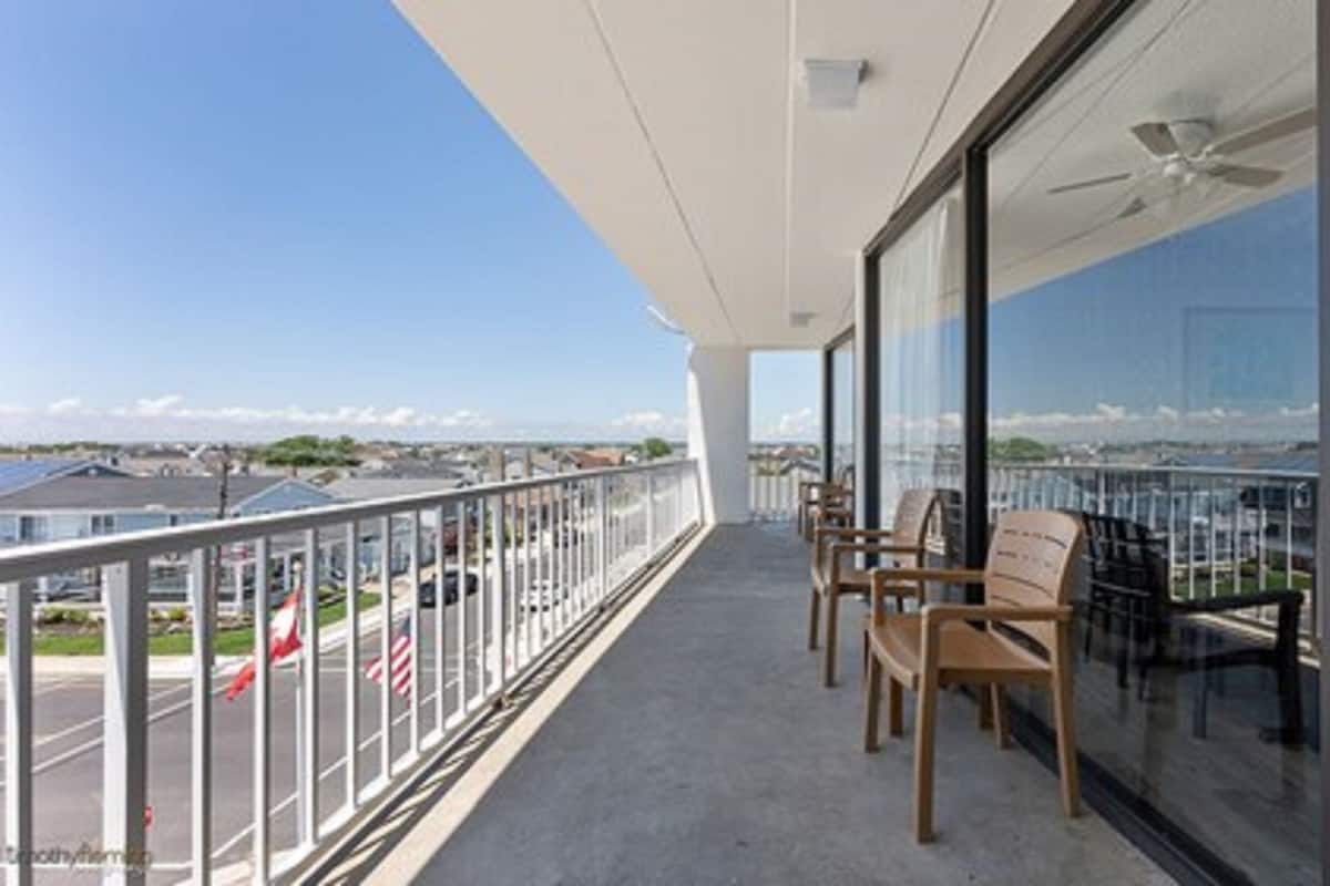 A balcony with a view of the city, equipped with a ceiling fan and seating.