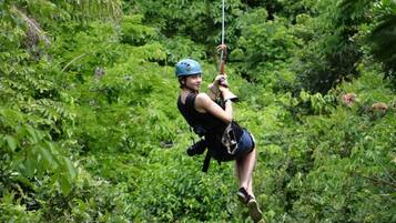 Una persona che vola su una zipline attraverso una fitta foresta verde.