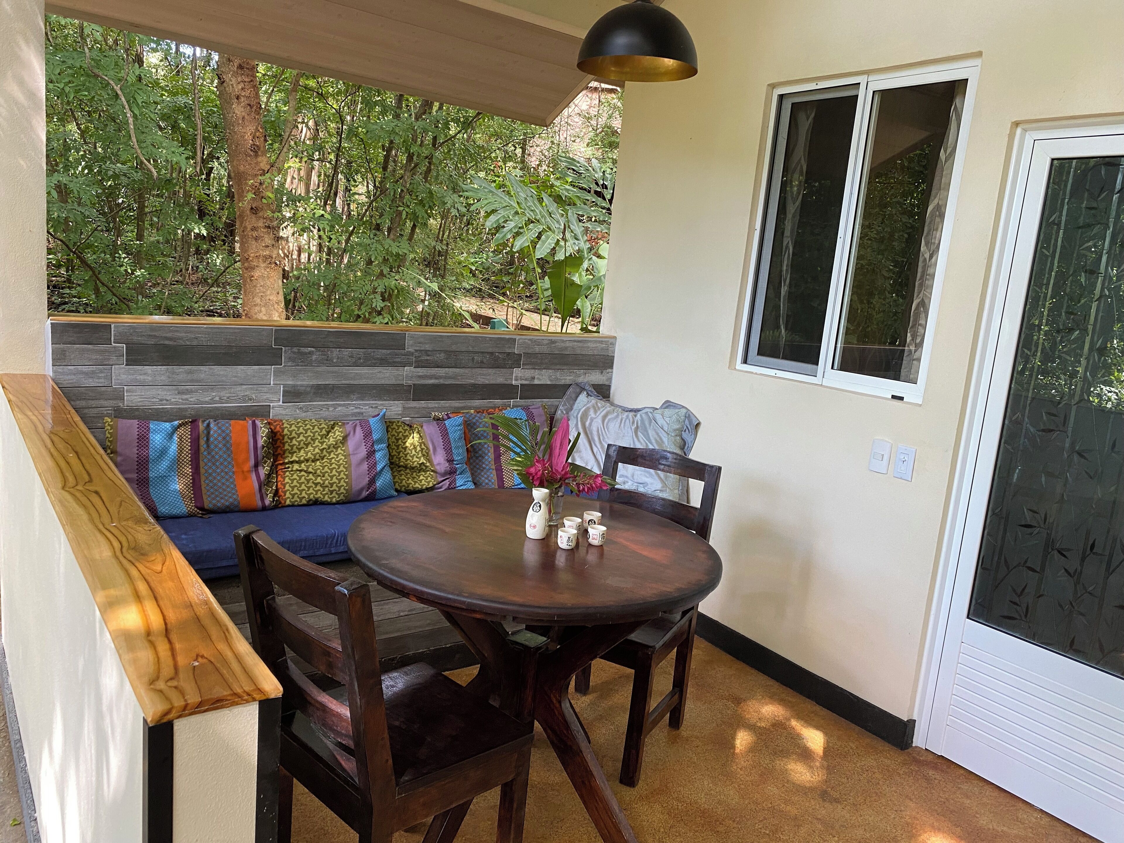 A cozy outdoor seating area with a wooden bench, a round table, and chairs.