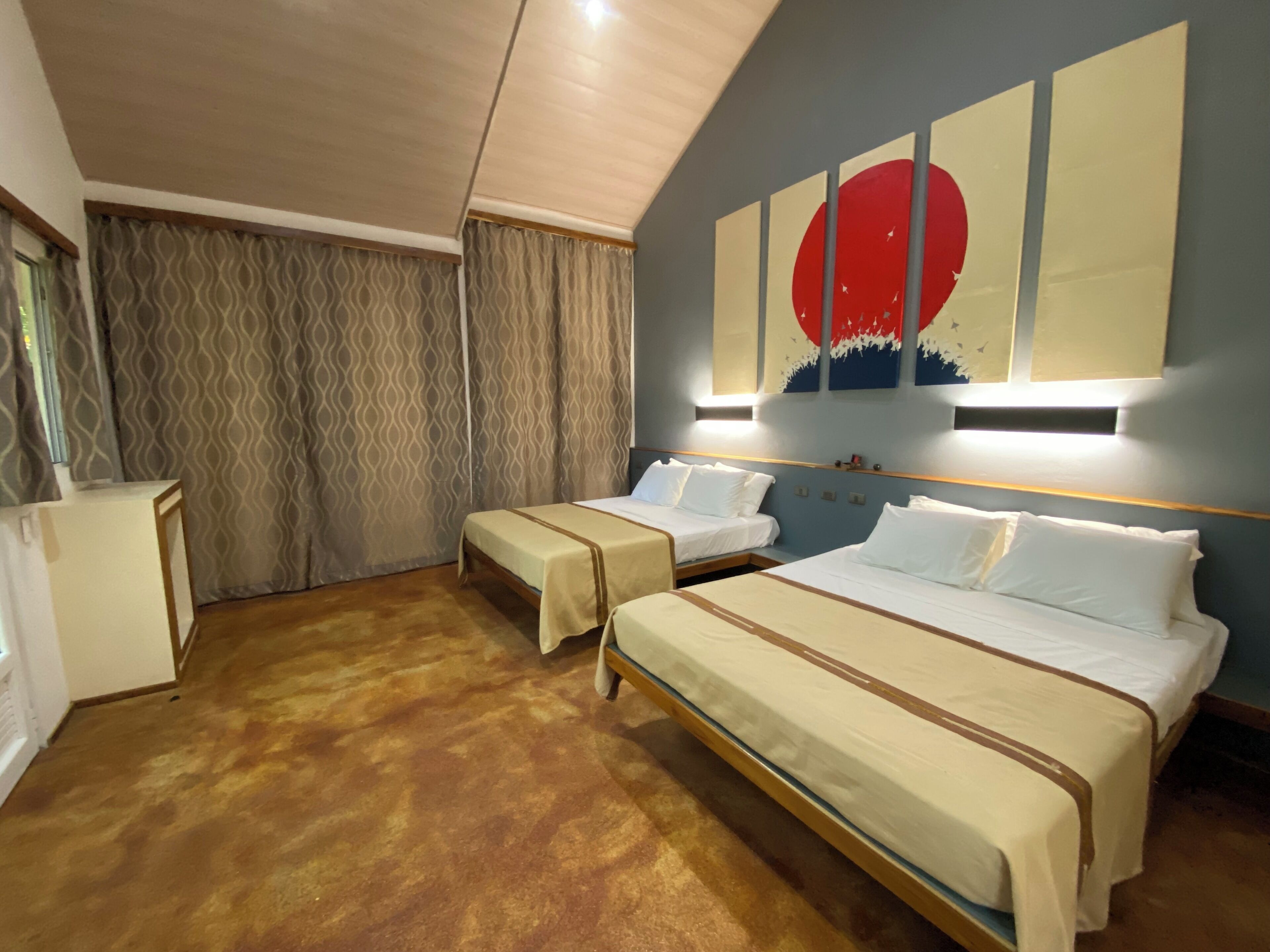 A hotel room with two beds, a desk, and a large wall painting.