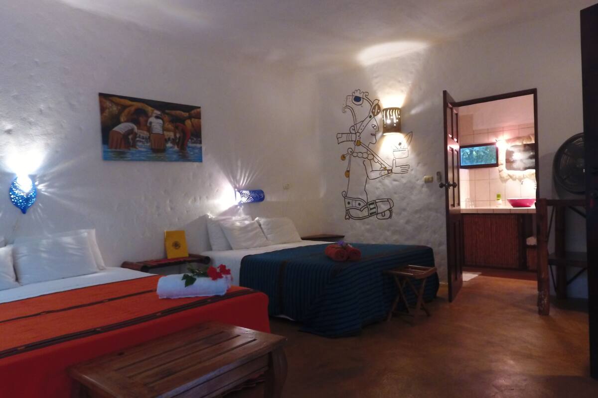 Een gezellige kamer met een bed, een bank, een klein tafeltje, en een muur met een schilderij en een lamp.