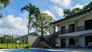 Una casa moderna con piscina, balcón y pared de piedra.