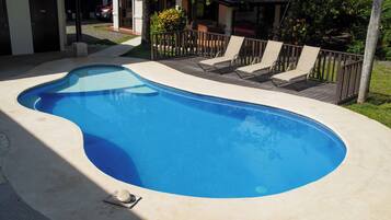 Una piscina al aire libre, sillones reclinables de piscina