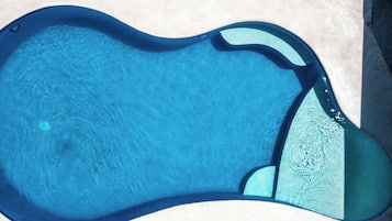 Una piscina al aire libre, sillones reclinables de piscina