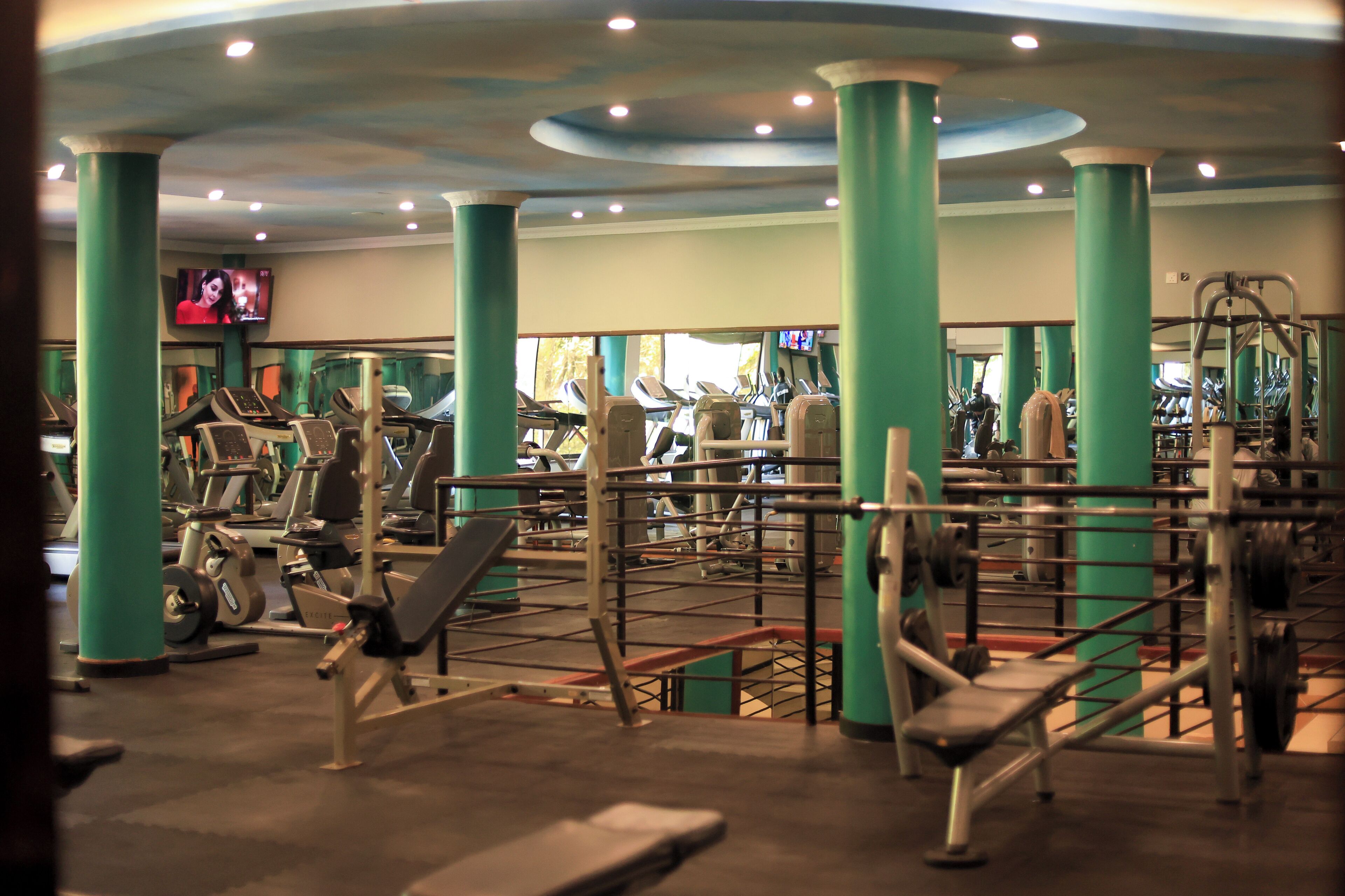 A gym with various exercise equipment, including treadmills, weight machines, and free weights.