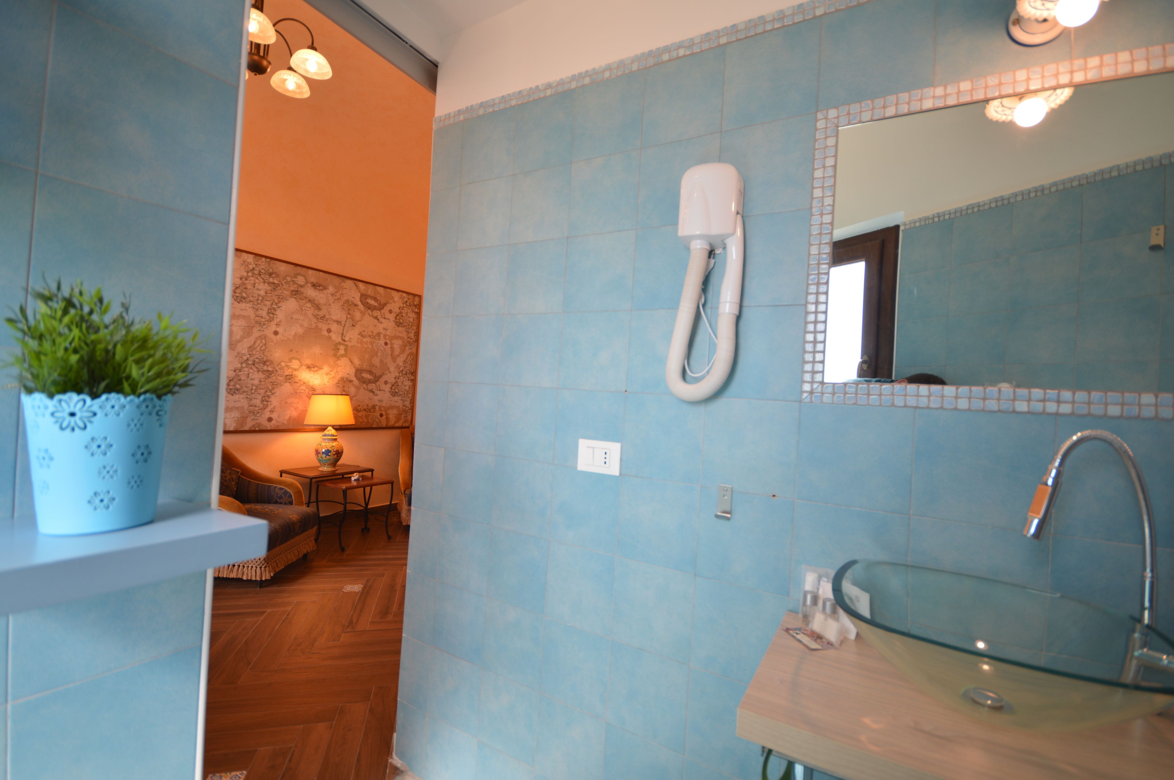 A bathroom with a glass sink, a towel rack, and a potted plant.