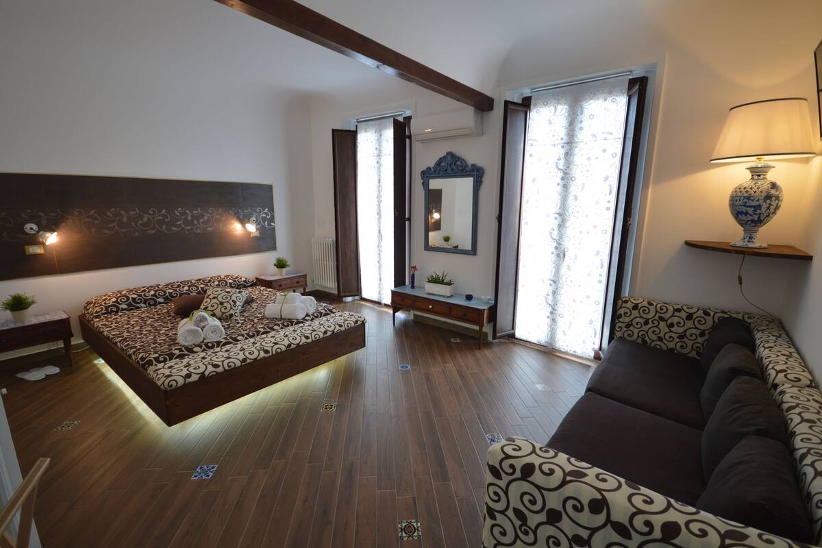 A modern bedroom with a bed, a sofa, and a lamp.