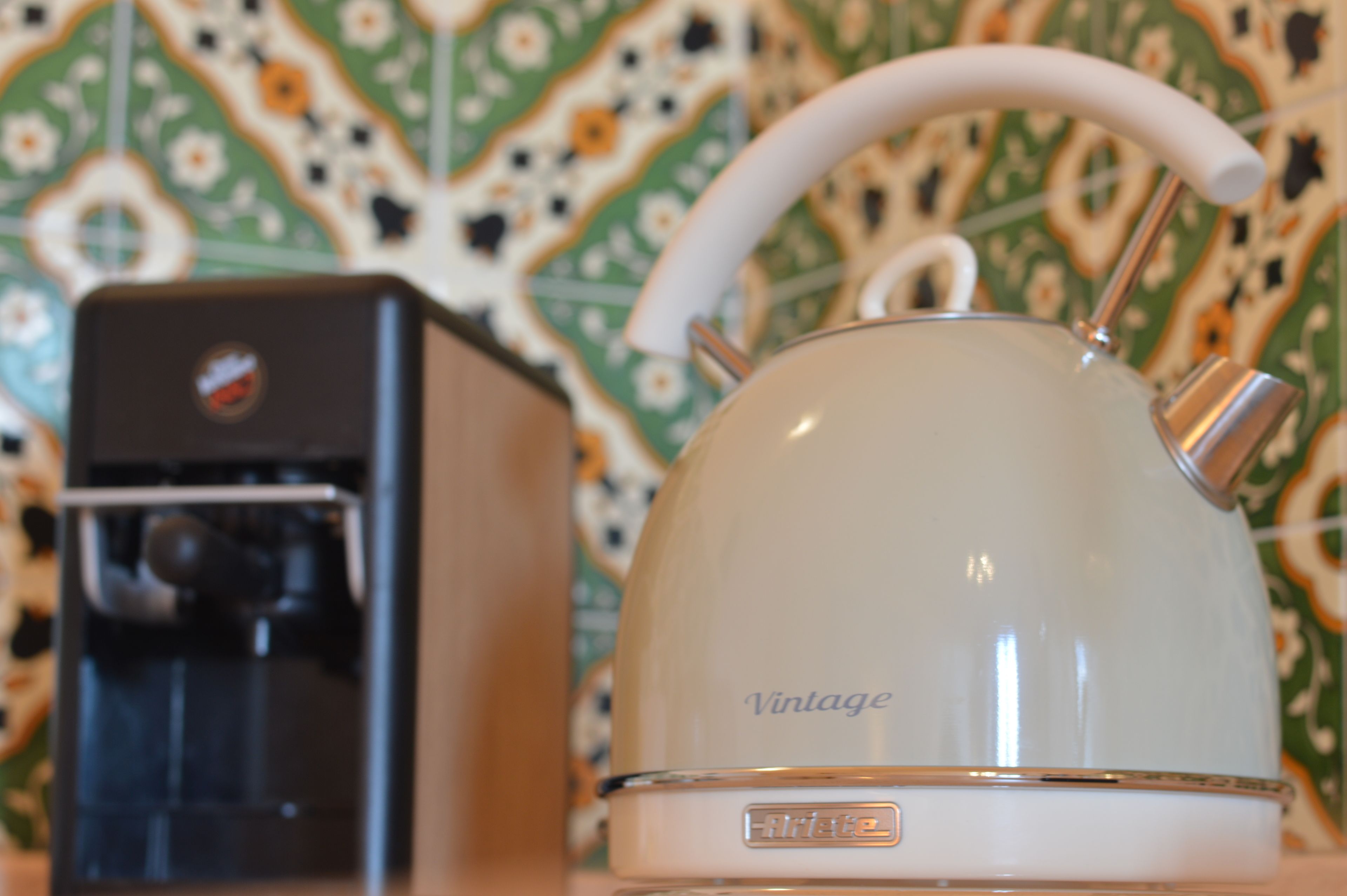 A vintage-style kettle with a handle and a coffee maker with a logo.