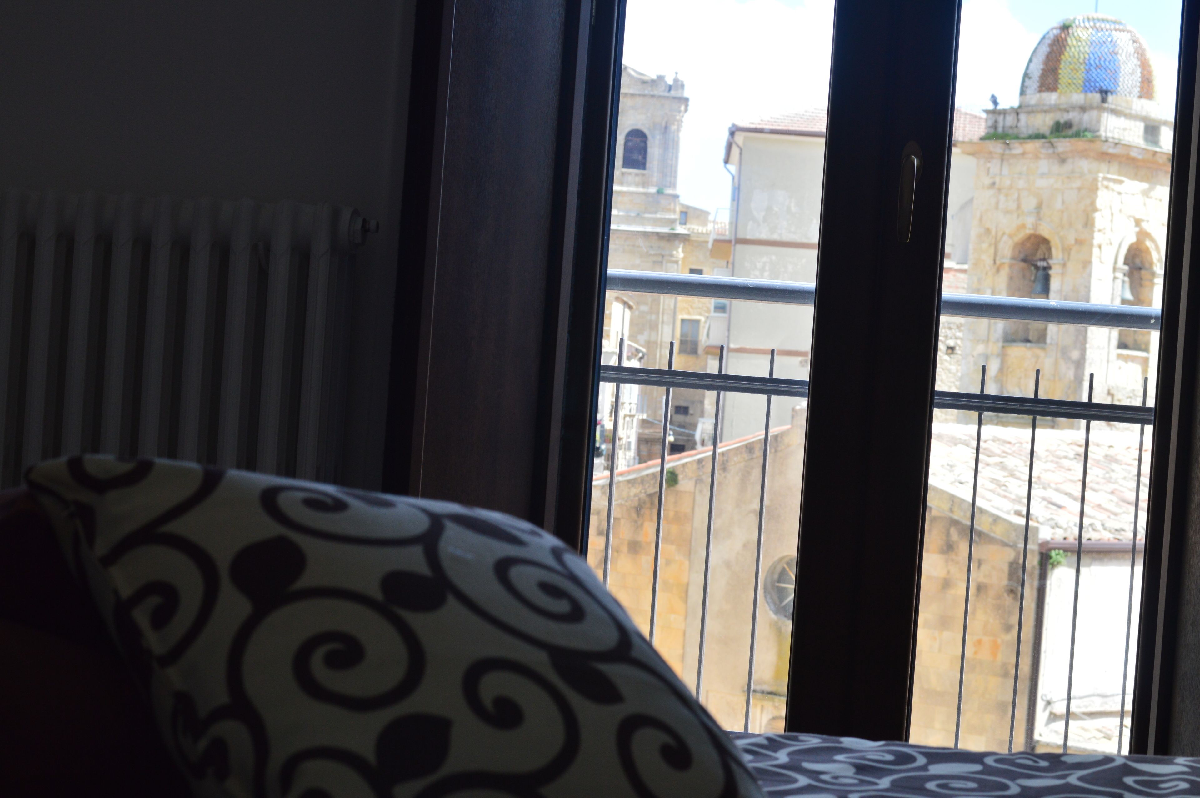 Habitació amb vista a un edifici històric a través d'una finestra amb barana de metall.