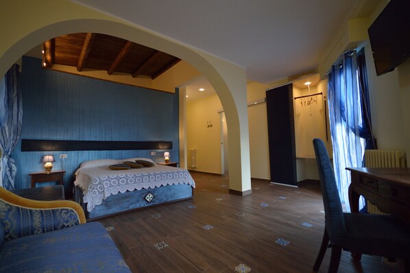 Quarto com cama, cadeira, mesa e teto de madeira.