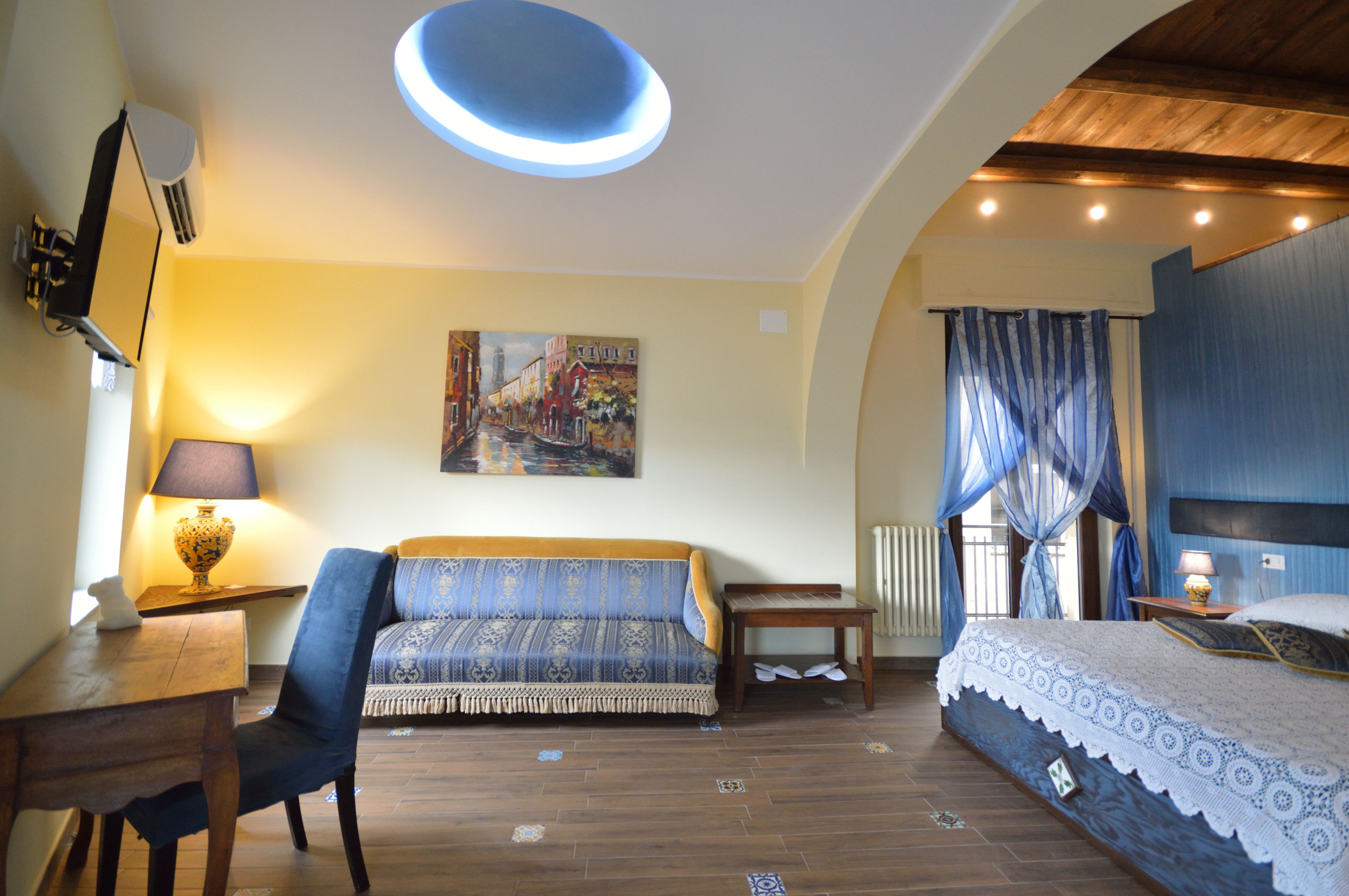Un dormitorio con cama, sofá, mesa y un cuadro en la pared.