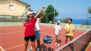 Una cancha de tenis con cuatro personas, una red y pelotas de tenis.