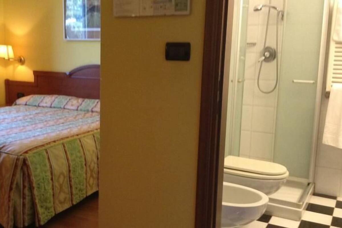 A bedroom with a bed, a bedside lamp, and a small window.