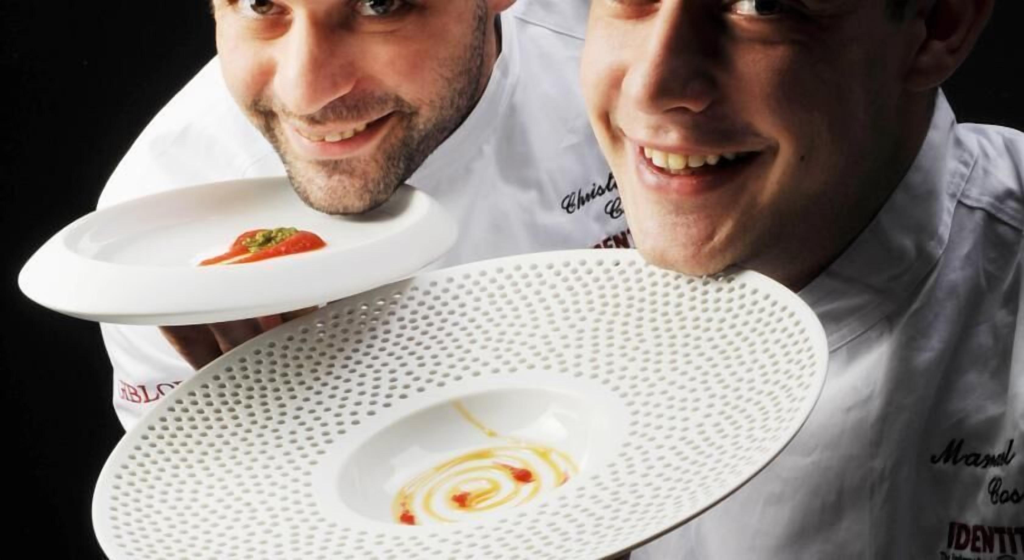 Dos cocineros sosteniendo platos con comida.