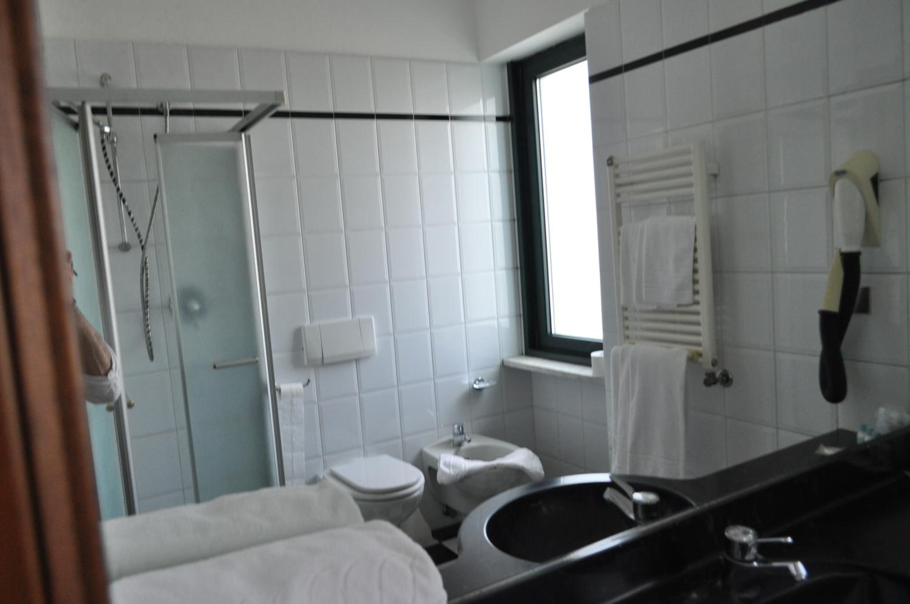 A modern bathroom with a shower, toilet, bidet, sink, and a large mirror.