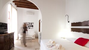 A hotel room with a bed, a TV, a chair, and a wooden ceiling. - Petit Hotel Algaida  (Algaida)