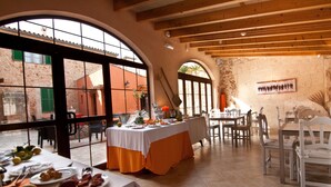 An indoor dining area with tables set for a meal, large windows, and a rustic interior. - Petit Hotel Algaida  (Algaida)