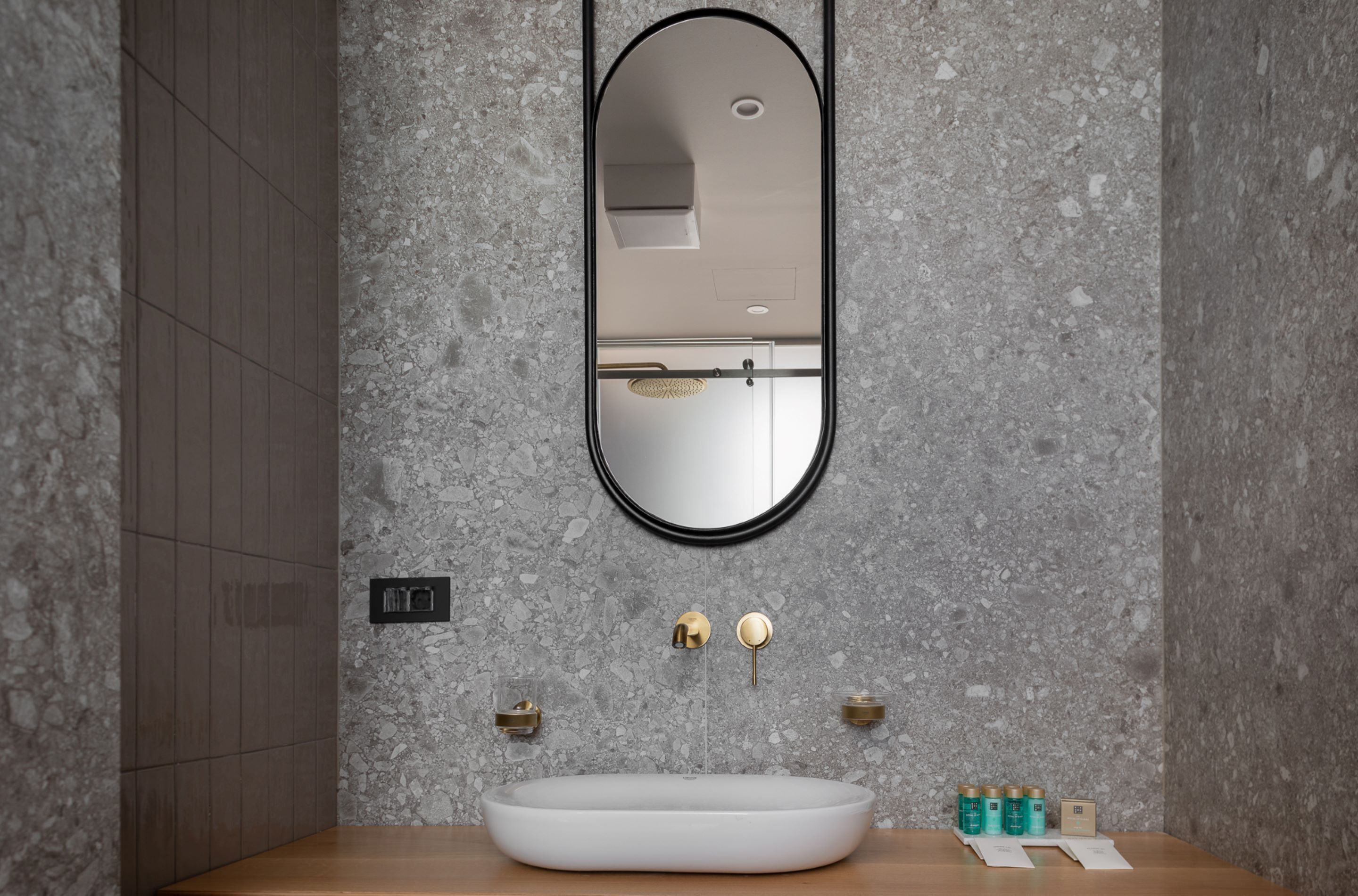 A bathroom with a white sink, a round mirror, and a textured wall.