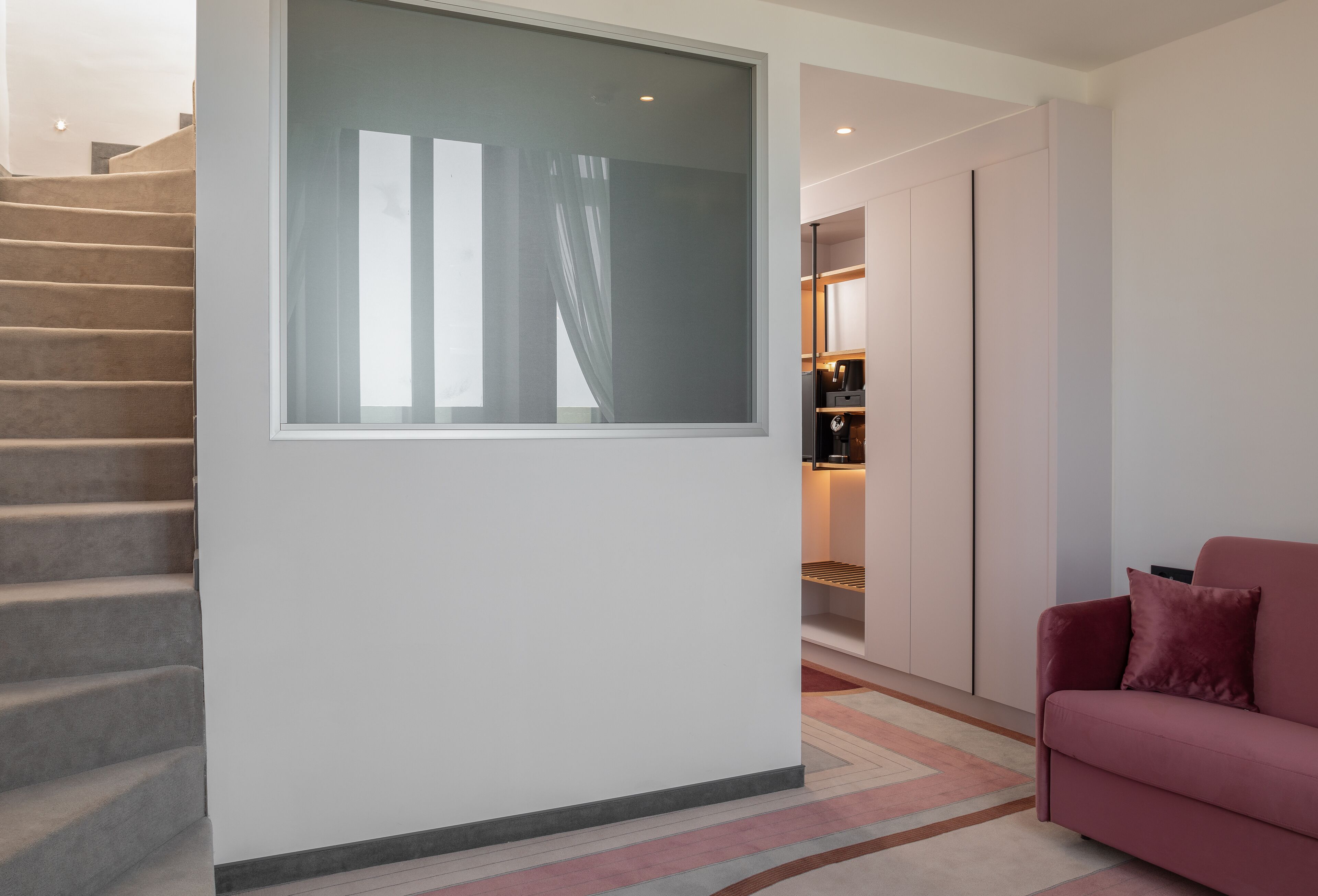 Un interno moderno con una scala, un'ampia finestra, un divano e un design minimalista.