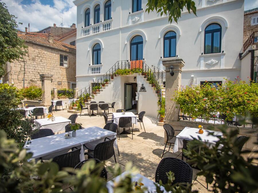 A courtyard with outdoor seating, a staircase, and a building with arched windows.