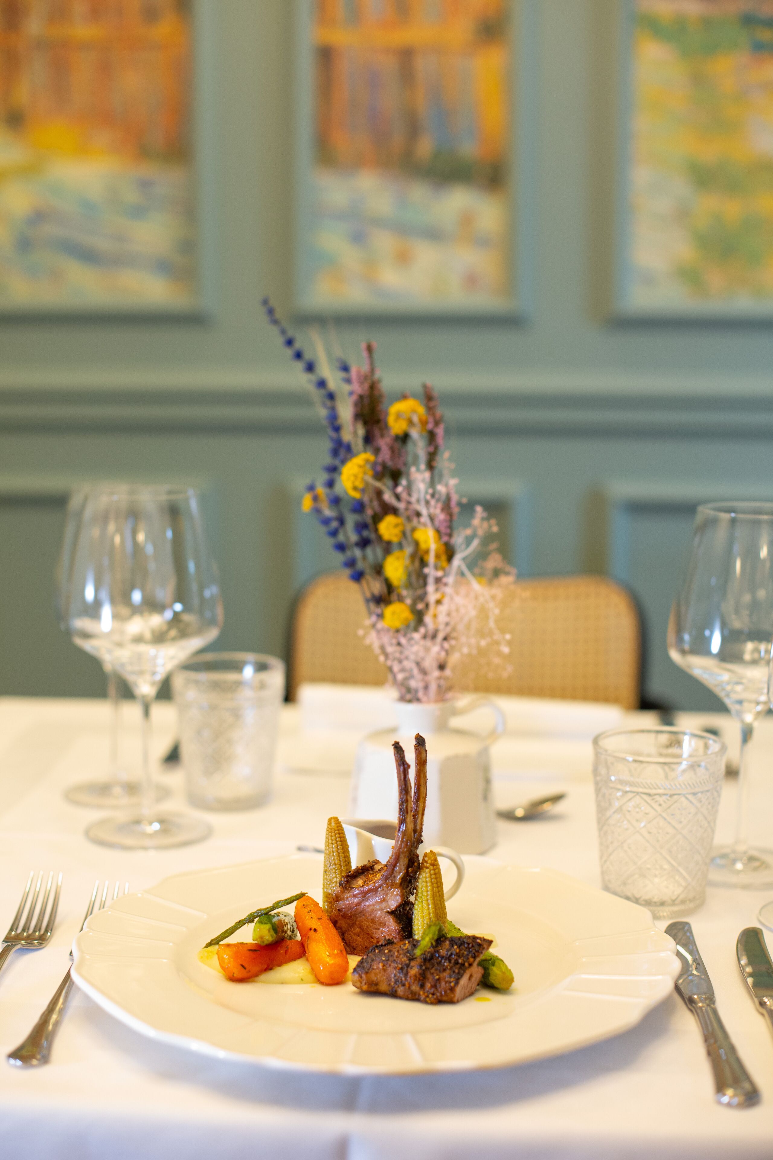 A dining table with a plate of food, wine glasses, and cutlery.