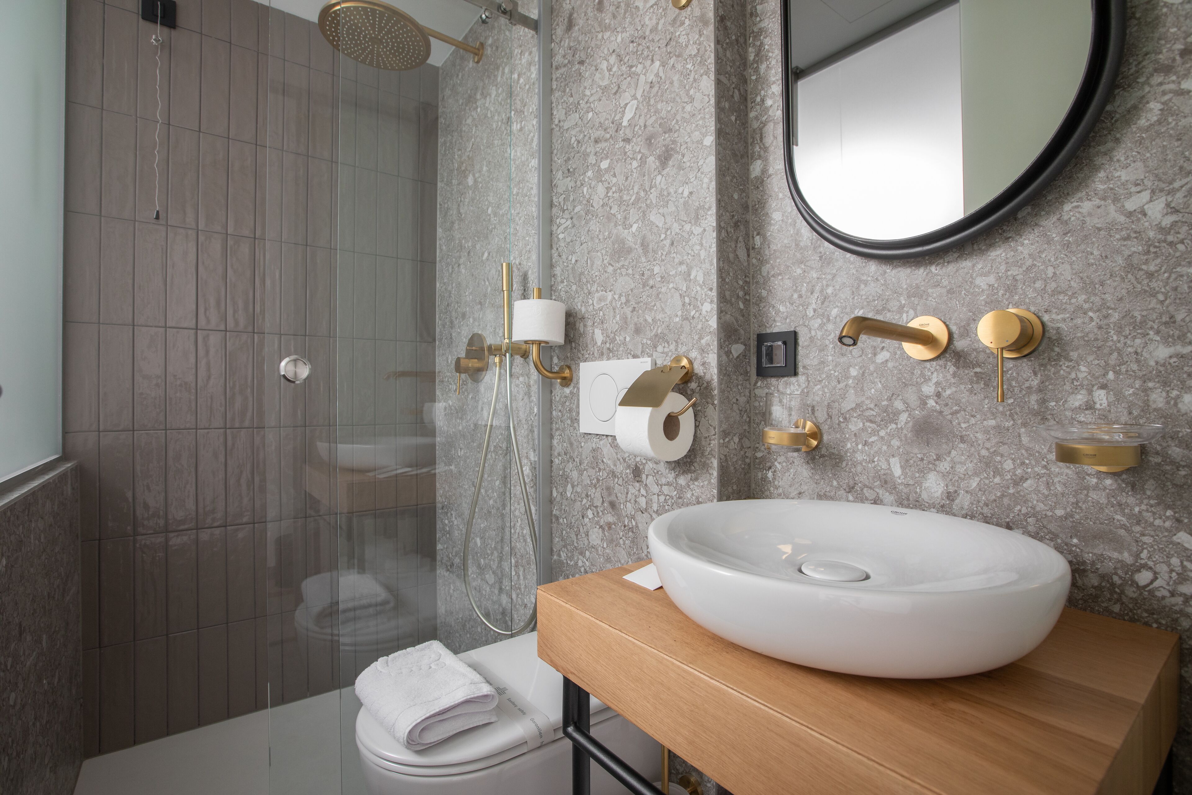 Un baño moderno con un lavamanos grande de color blanco, una ducha con puerta de vidrio y un espejo sobre el lavamanos.