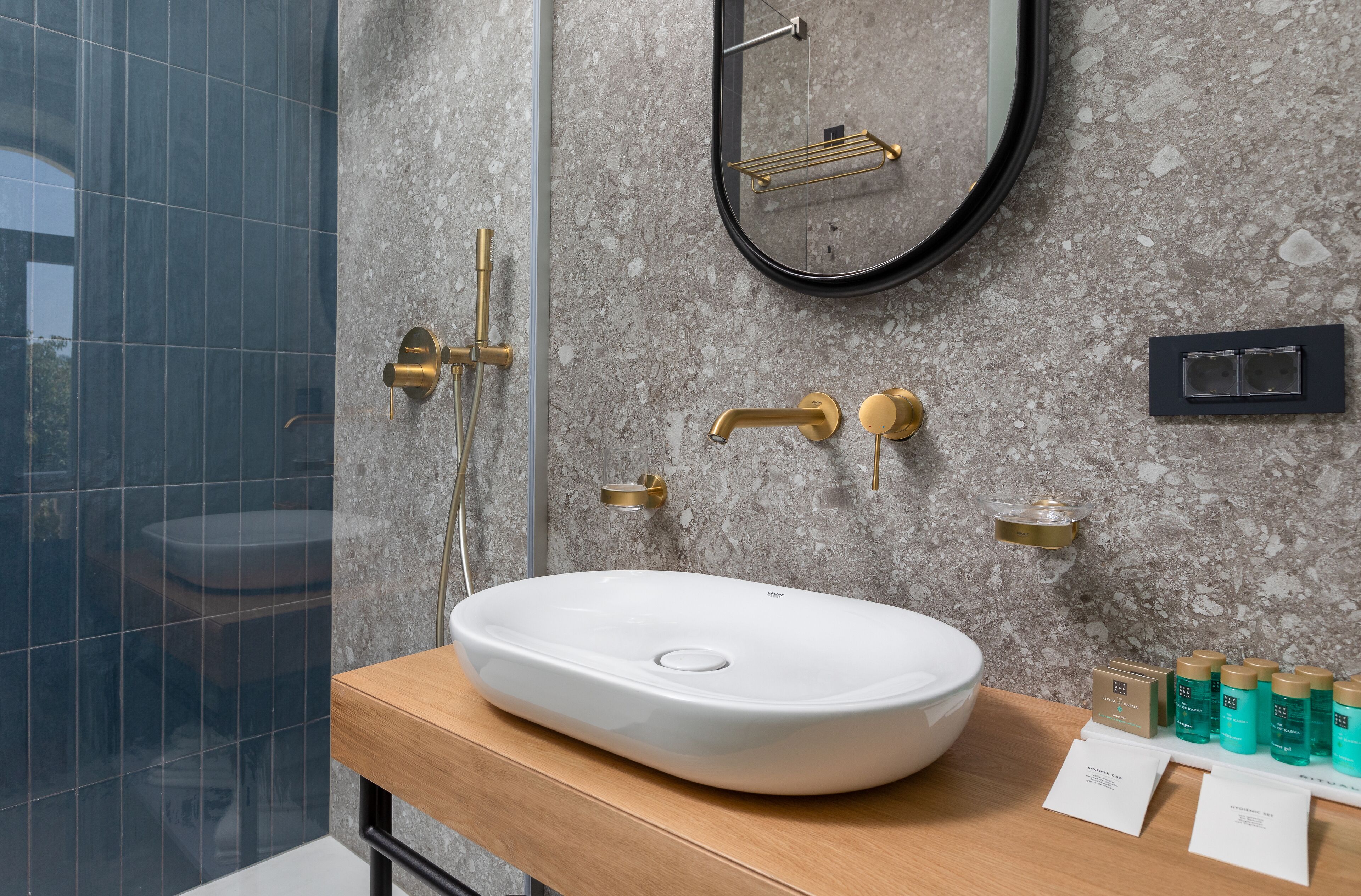 A modern bathroom with a large oval sink, a mirror, and a shower area.