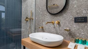 A modern bathroom with a large oval sink, a mirror, and a shower area.