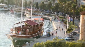 Una zona frente al agua con un barco grande amarrado en el muelle, rodeada de edificios y palmeras.