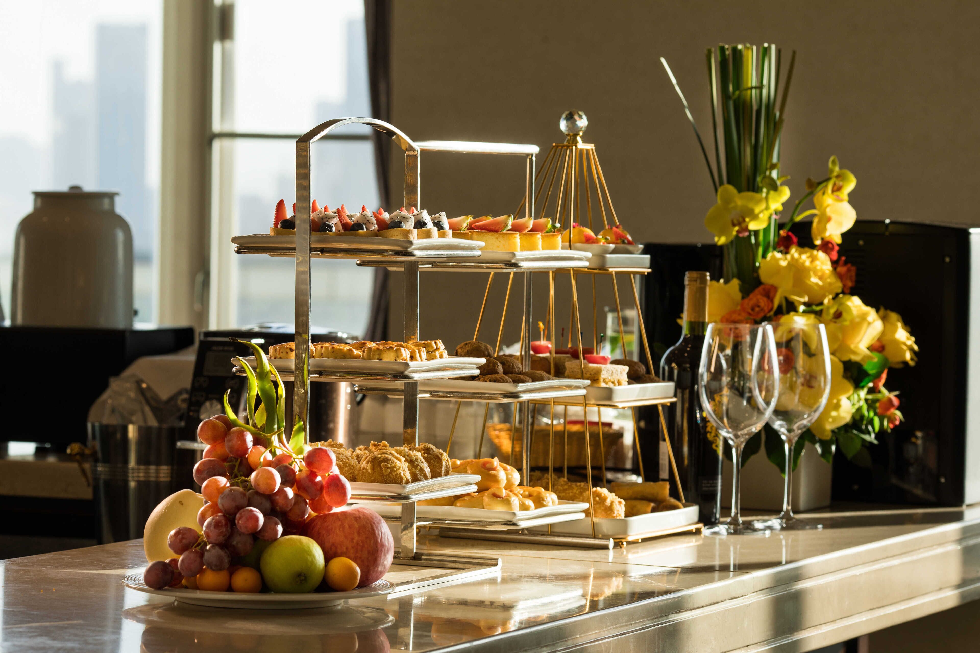 A buffet setup with various food items and a vase of flowers.