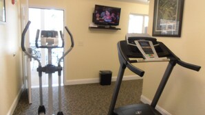 A room with a treadmill, an elliptical machine, and a television on the wall. - Affordable Suites Augusta (Augusta)
