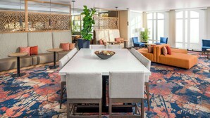 A modern hotel lobby with a long dining table, comfortable seating, and large windows. - Hilton Garden Inn Ogden UT (Ogden)