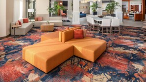 A spacious living area with a large sectional sofa, a dining table with chairs, and a kitchen area in the background. - Hilton Garden Inn Ogden UT (Ogden)