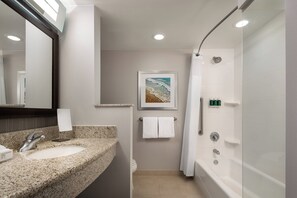 A modern bathroom with a granite sink, a large mirror, a framed picture of a beach, a toilet, a shower, and a bathtub. - Courtyard Maui Kahului Airport (Kahului)