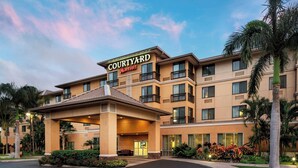 Un hotel Courtyard Marriott con entrada cubierta, varios balcones y un exuberante paisaje.