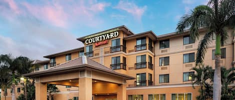 A Courtyard Marriott hotel with a covered entrance, multiple balconies, and lush landscaping.