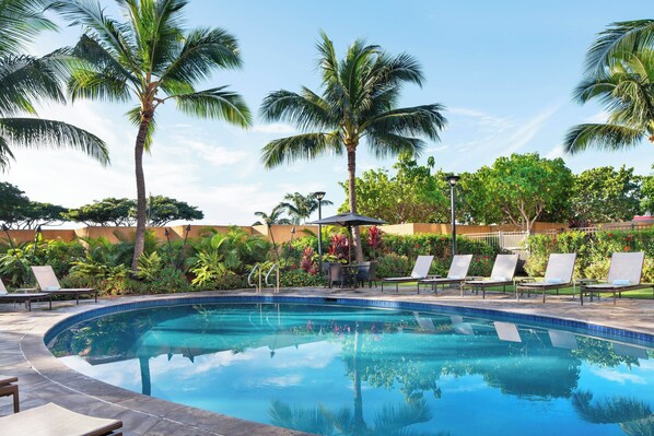 Een buitenzwembad, parasols bij het zwembad en ligstoelen