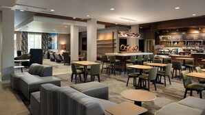 Un moderno vestíbulo de hotel con zonas de estar, un bar y una estación de café.