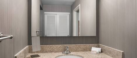 A bathroom with a granite countertop, a sink, a mirror, and a towel rack.