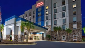 Un hôtel Hampton Inn & Suites au design moderne, avec une façade en pierre et un mur d’accent bleu.